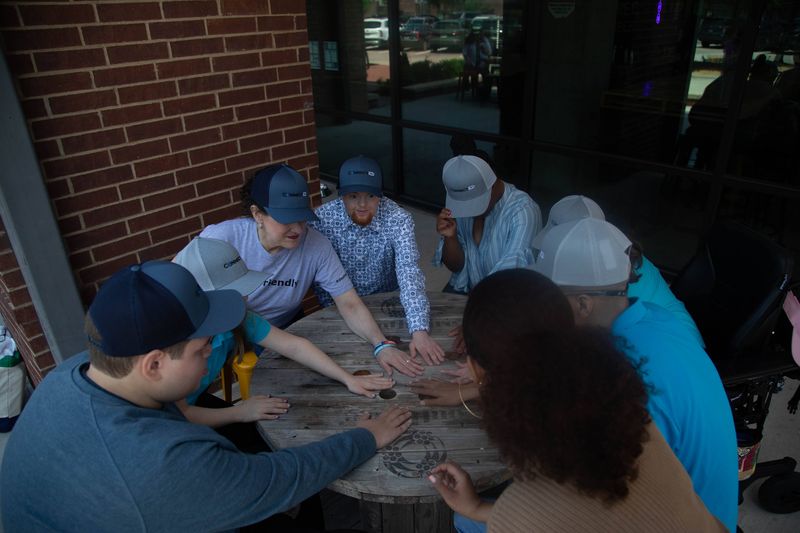 Friends in matching caps put their hands together over a wooden table.