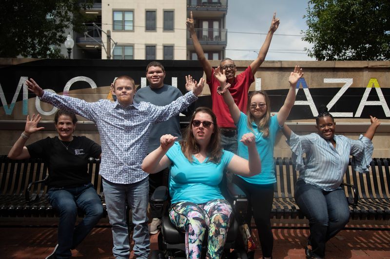 A group of friends cheers with their arms in the air.